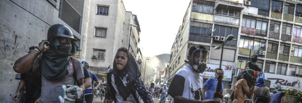 Anti-government activists scatter upon being charged by riot police during a protest against the election of a Constituent Assembly proposed by Venezuelan President Nicolas Maduro, in Caracas on July 30, 2017.
Deadly violence erupted around the controversial vote, with a candidate to the all-powerful body being elected shot dead and troops firing weapons to clear protesters in Caracas and elsewhere. / AFP PHOTO / JUAN BARRETO